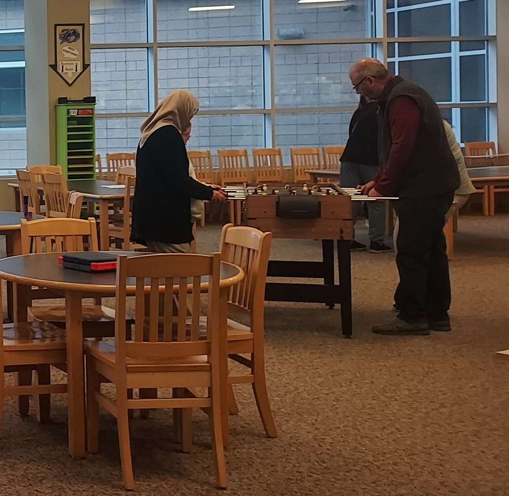 Staff and students playing foosball in the library