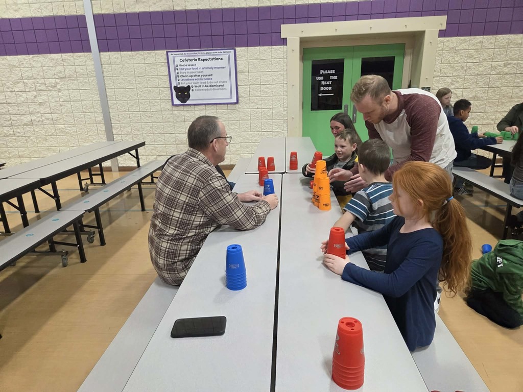 Mr. Bauman helping families playing cup stacking