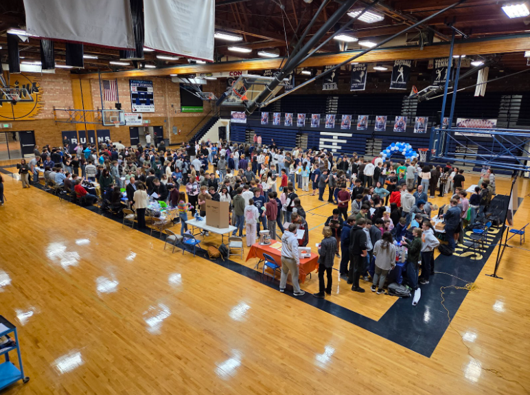 Twin Falls High School Gym lined with tables and filled with students stopping at each table to discover thei different programs offered by our district.
