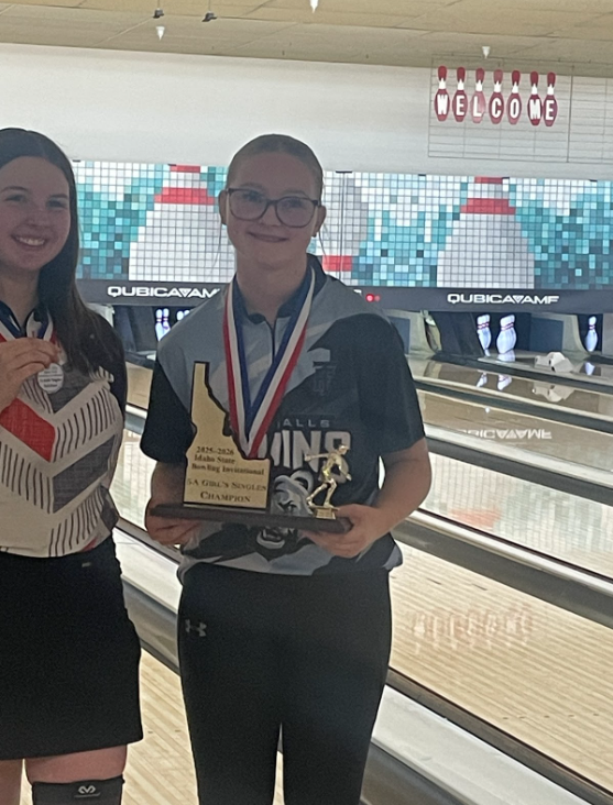 Student pictured in bowling ally holding Idaho shaped trophy that reads "5A Girl's Bowling Champion"