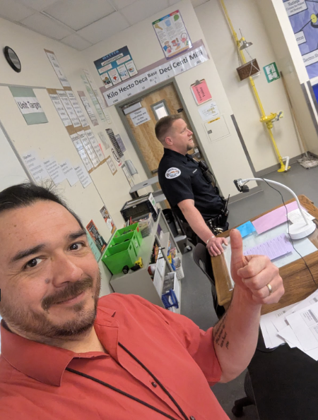 Mr. Ruiz taking a selfie with Officer Strassner talking to the class in the background