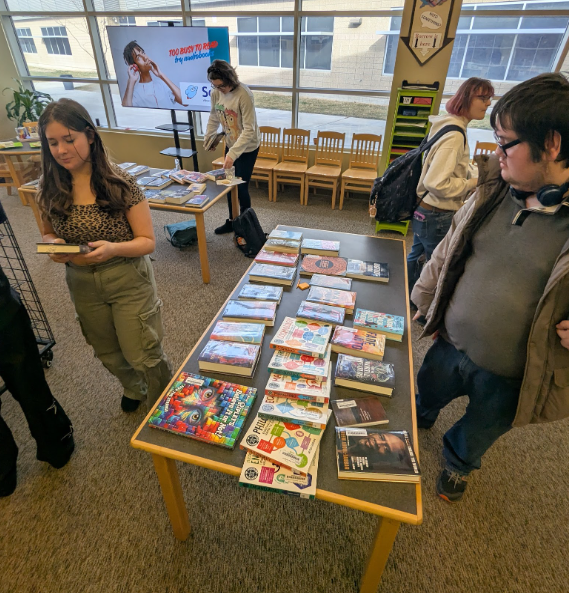 Students browsing over a table displayed with new books