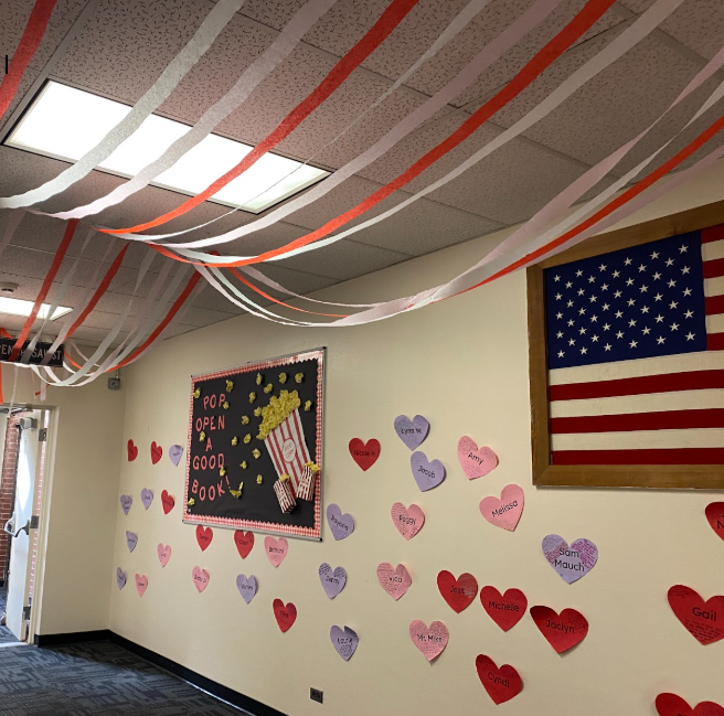 A hallway decorated for Valentine's Day. The wall are covered in hearts, each one written on, and the ceiling is draped with streamers.