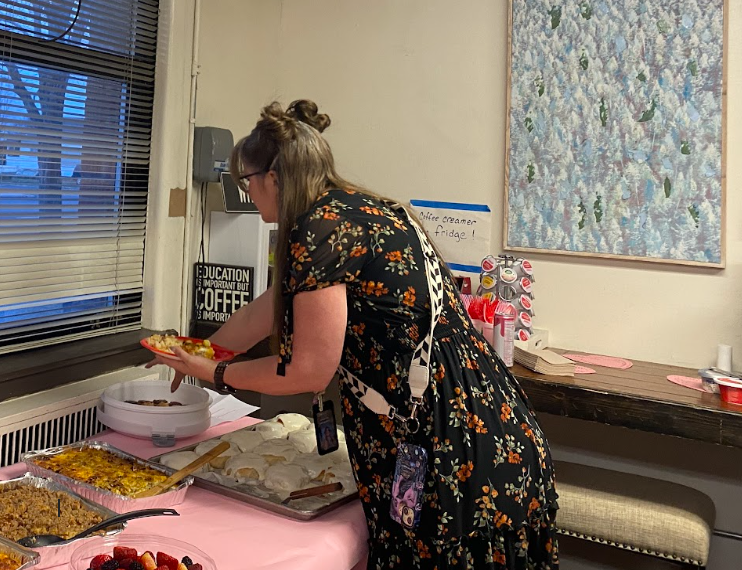 A staff member making a plate at a table full of a delicious looking breakfast spread