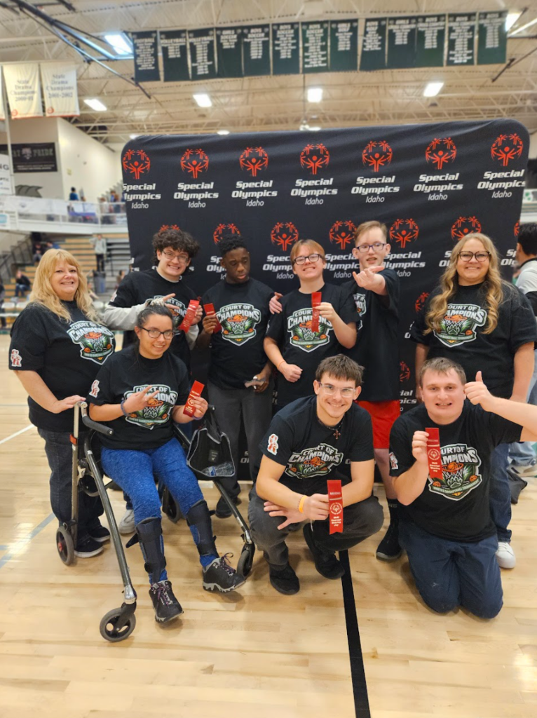 The team pictured together wearing their champion t-shirts and holding up ribbons