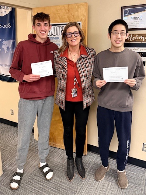 2 male students stand with female administrator while holding certificates