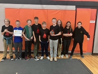 The team grouped together proudly showing off a trophy and certificate