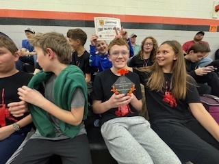 The team seated holding up a trophy and certificate
