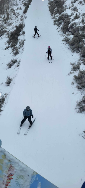 Three students skiing, pictured from the ski life above.