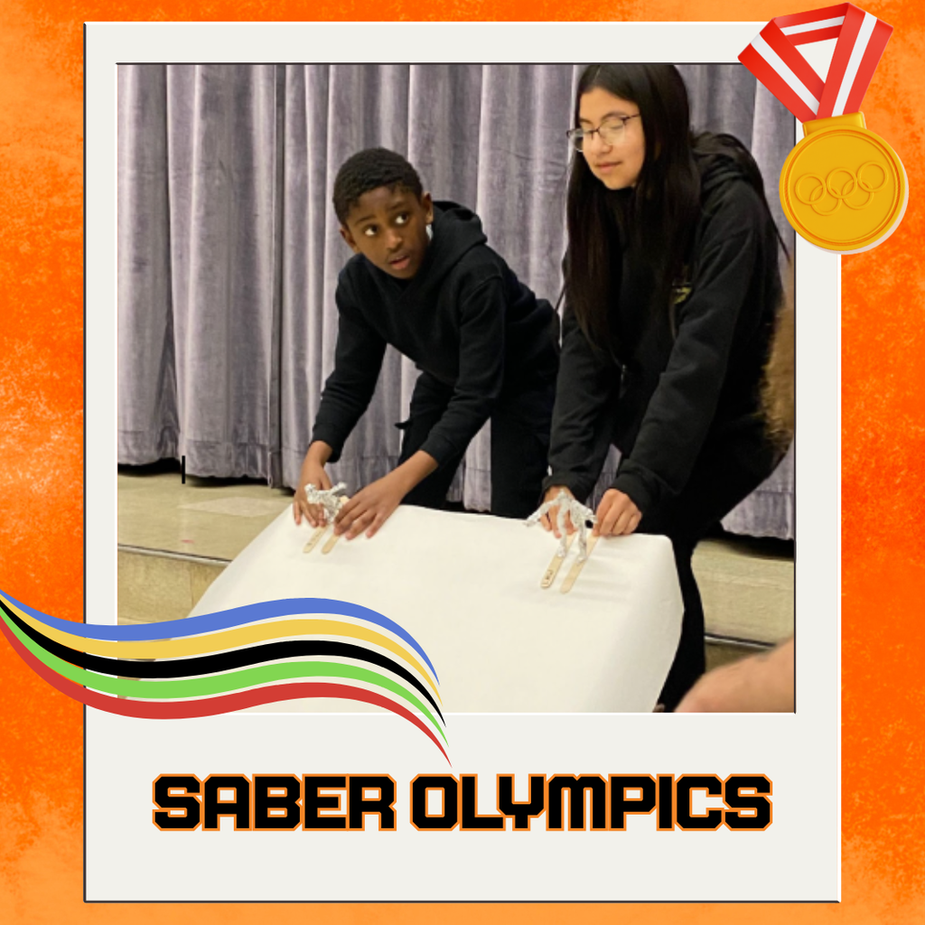 Students racing their "skiers" down the "slopes" aka a table angled down steps covered in white paper "snow"