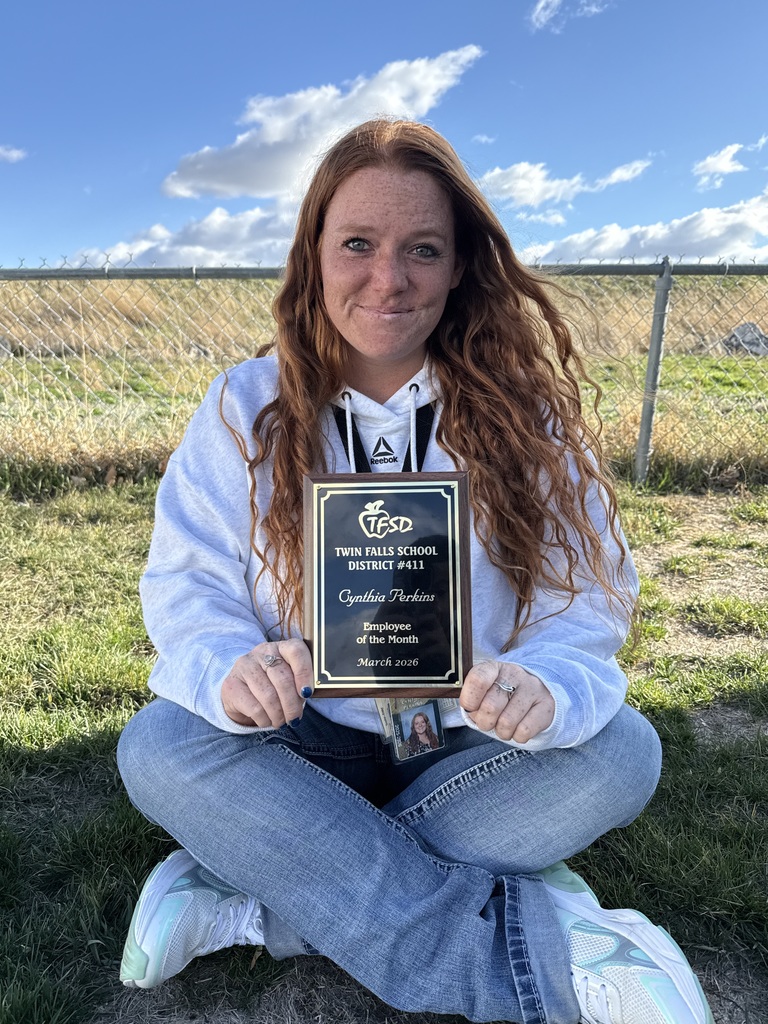 Employee of the month sitting in the grass holding plaque 