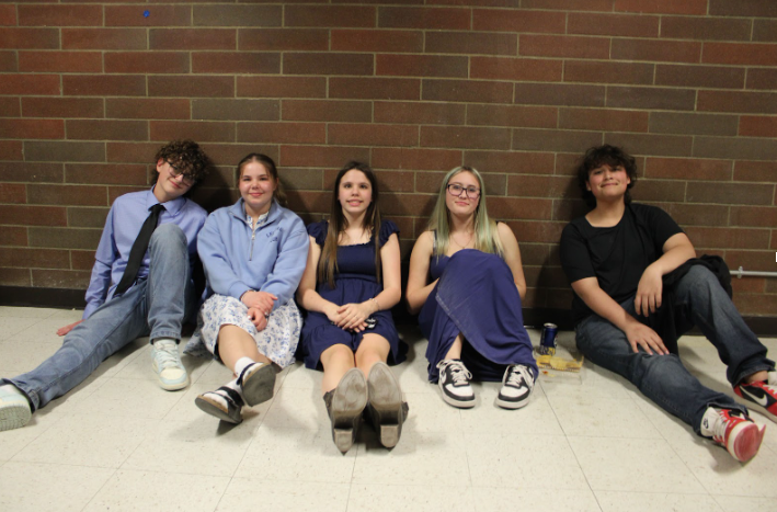 Five students sitting along a wall in their semi-formal attire.