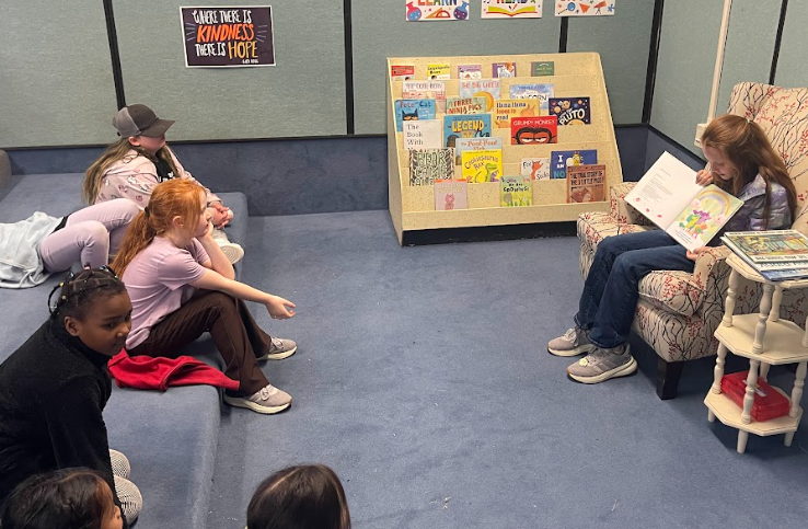 Student reading a book to other students