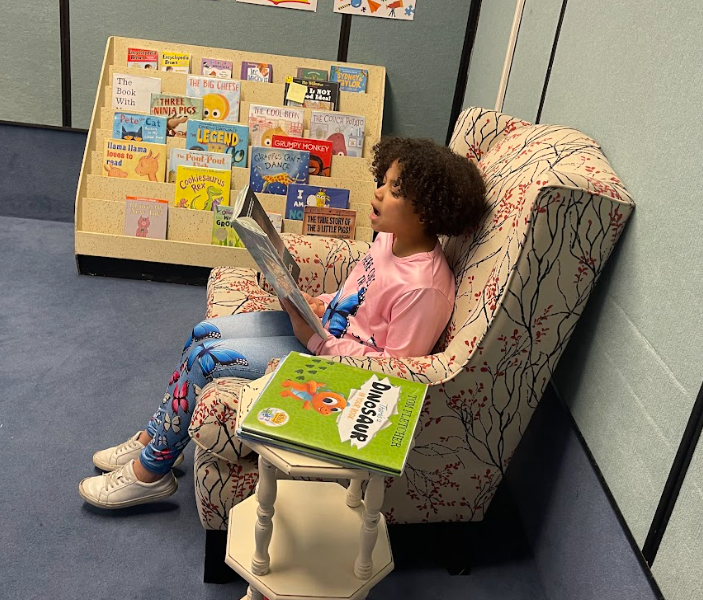 Student reading a book to other students