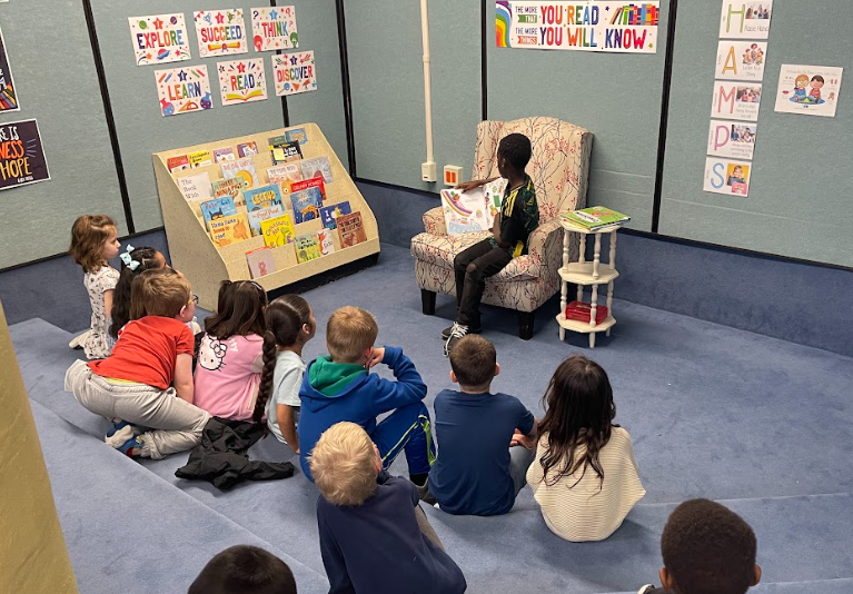 Student reading a book to other students