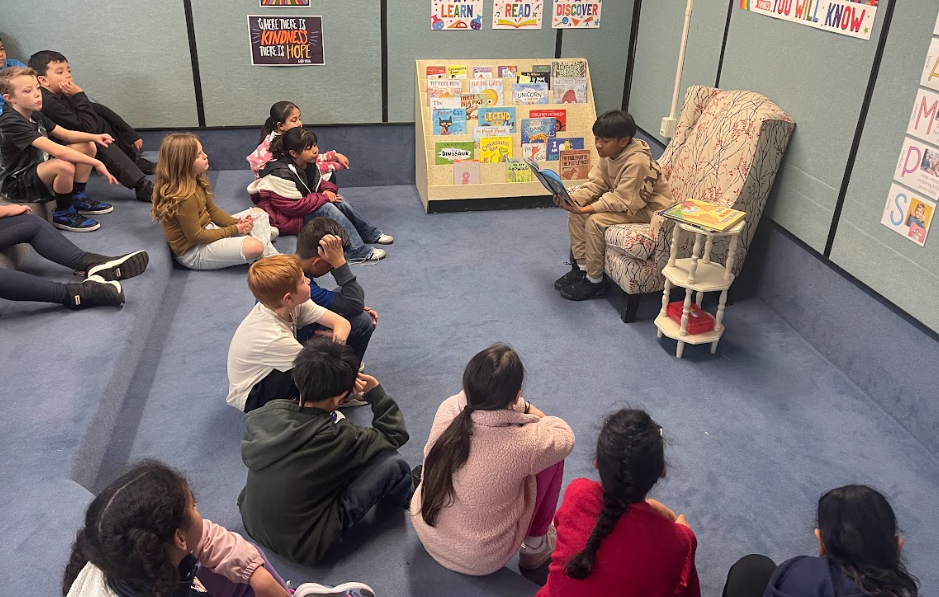 Student reading a book to other students