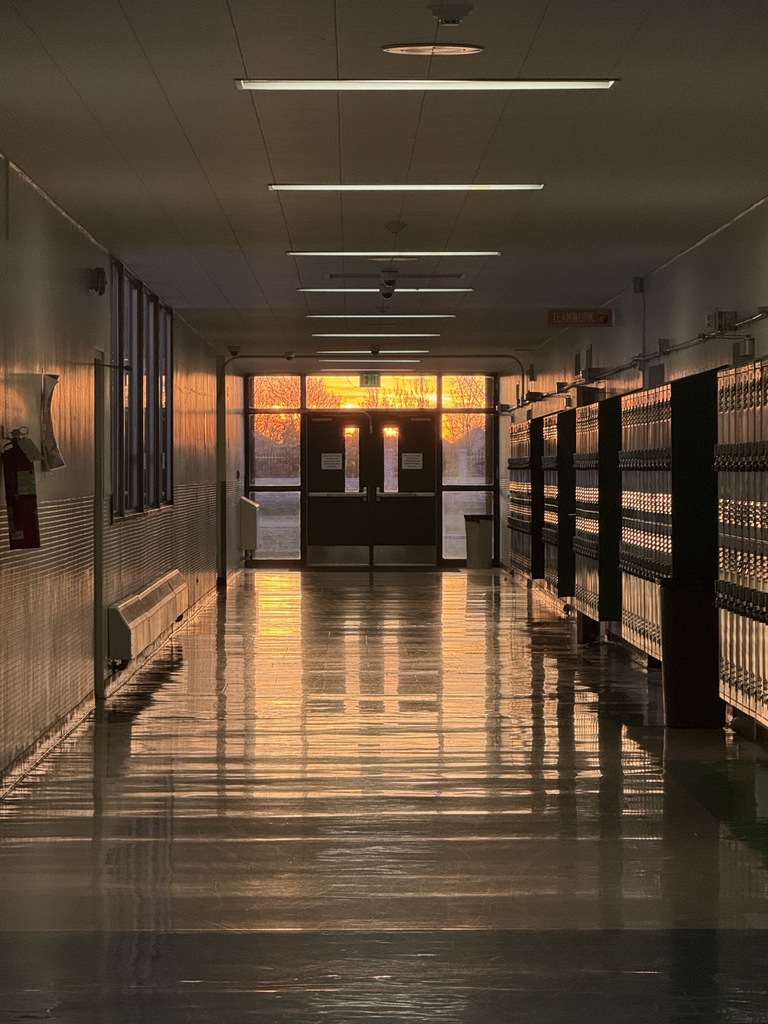 A picture of a school hallway with lockers and the setting sun. 