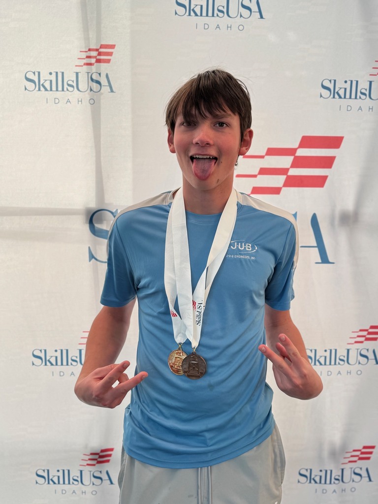 A student wearing two medals making a silly facial expression