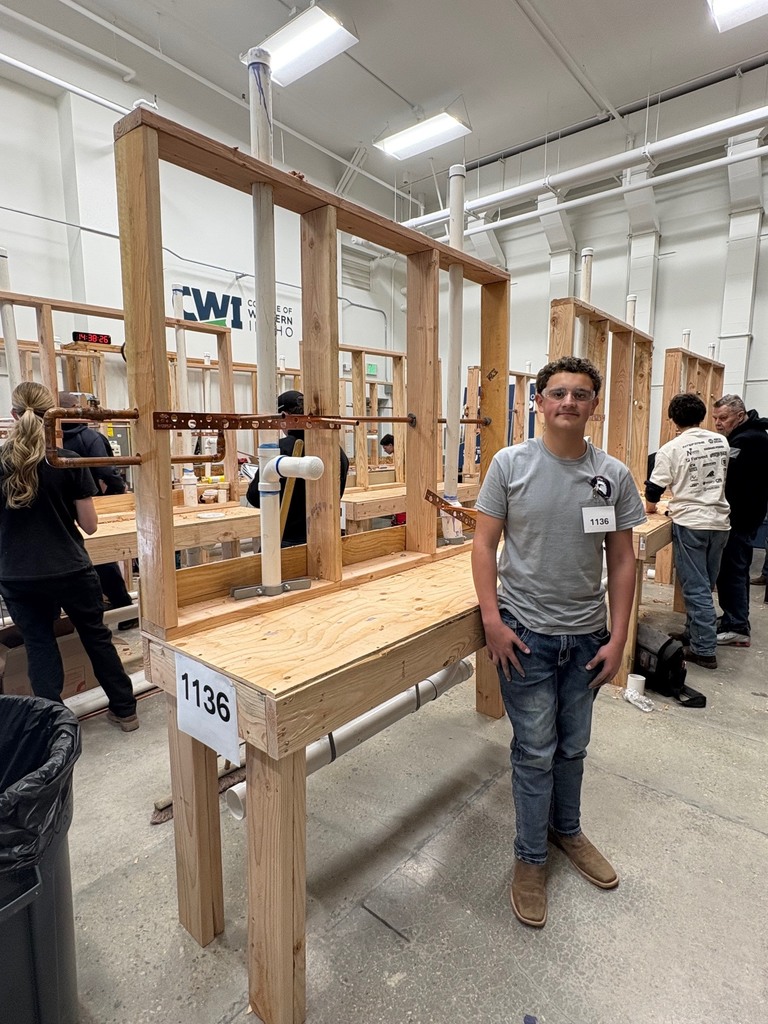 Miguel standing in front of his plumbing display