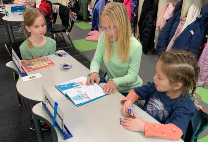 One older student reading to two younger buddys