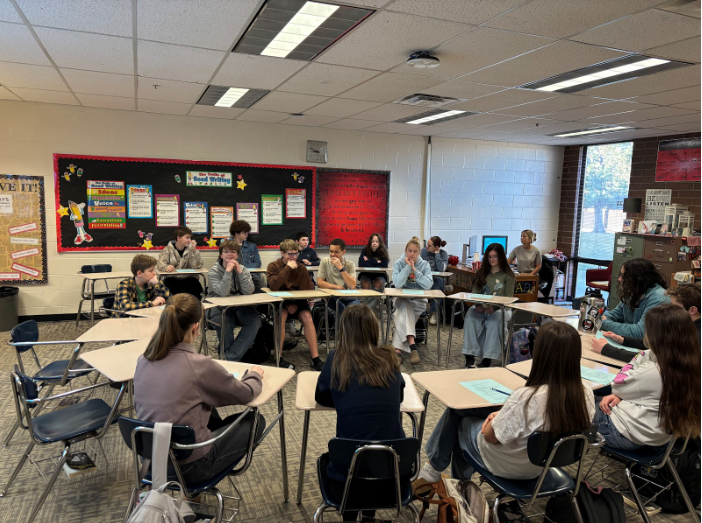 A classroom full of students with their desks gathered in one big circle