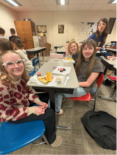 Three students sitting at a table enjoying the fruits of everyone's hard work.