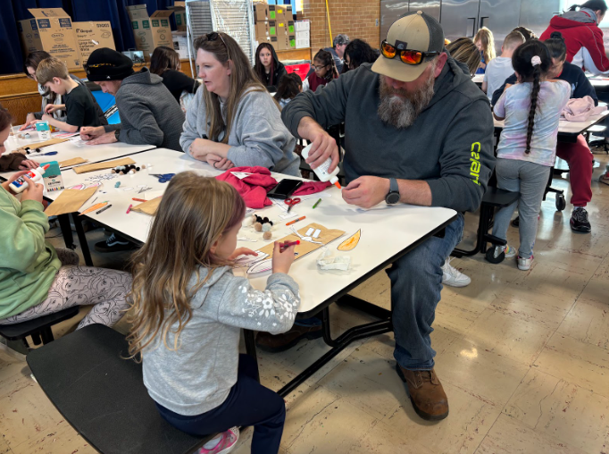 Families gathered at tables working together to assemble a craft.