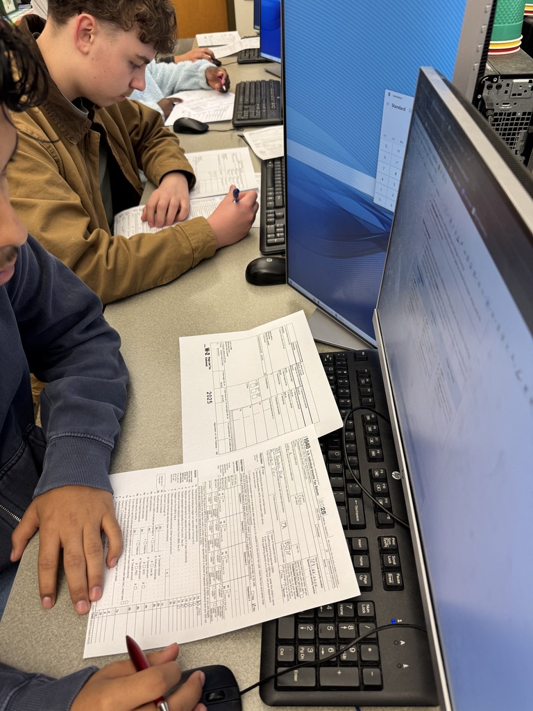 Students at tables filling out tax documents