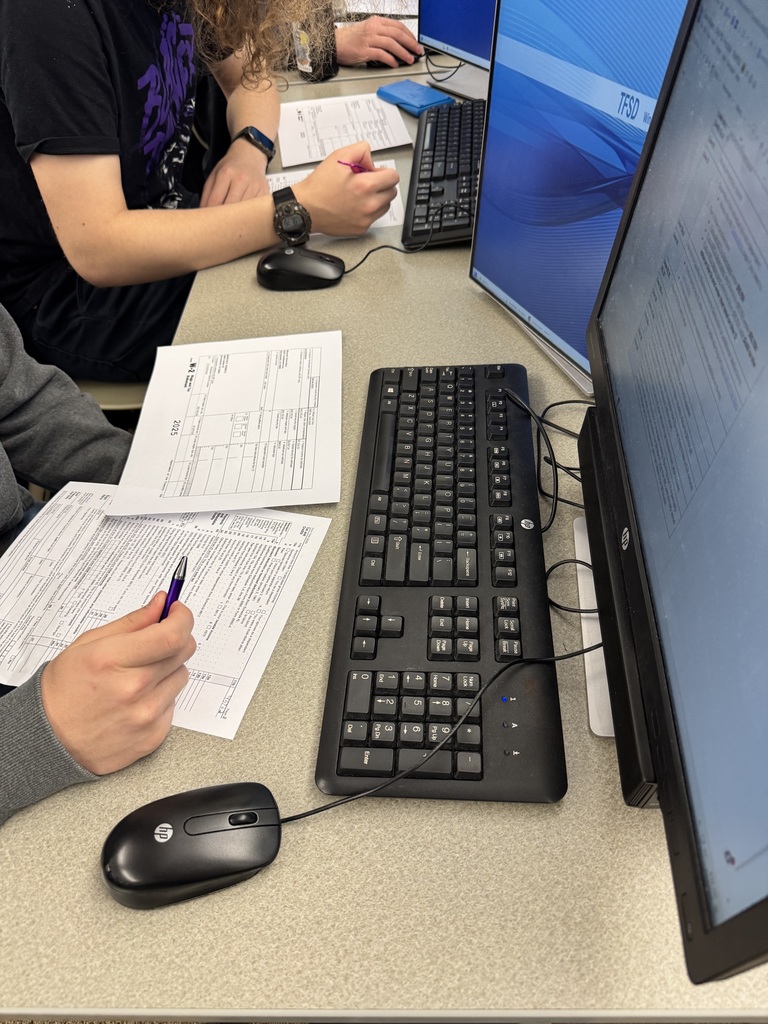 Students at tables filling out tax documents