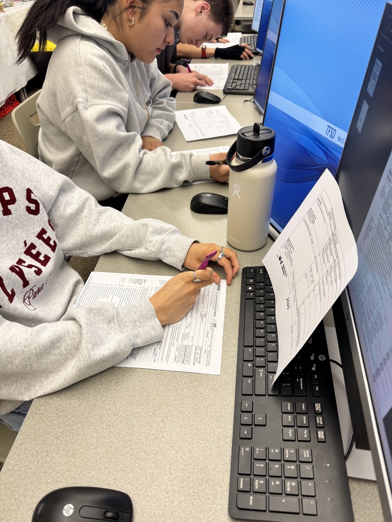 Students at tables filling out tax documents