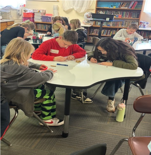 Students sitting at tables in a classroom, intently working on a project