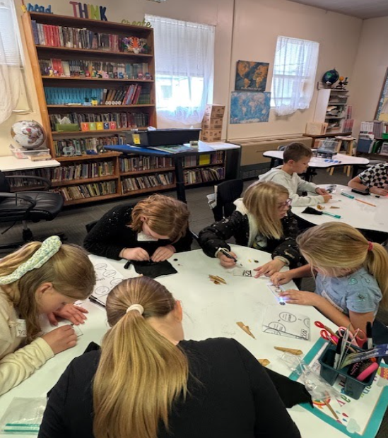 Students sitting at tables in a classroom, intently working on a project