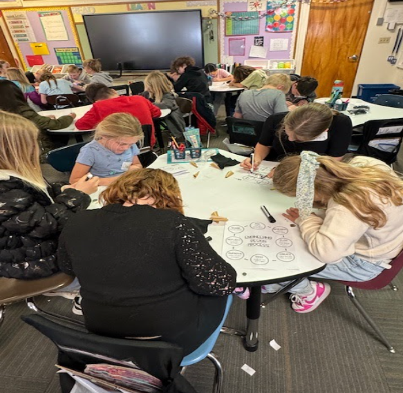 Students sitting at tables in a classroom, intently working on a project