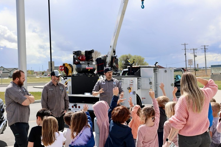Students listening to men talk about a crane