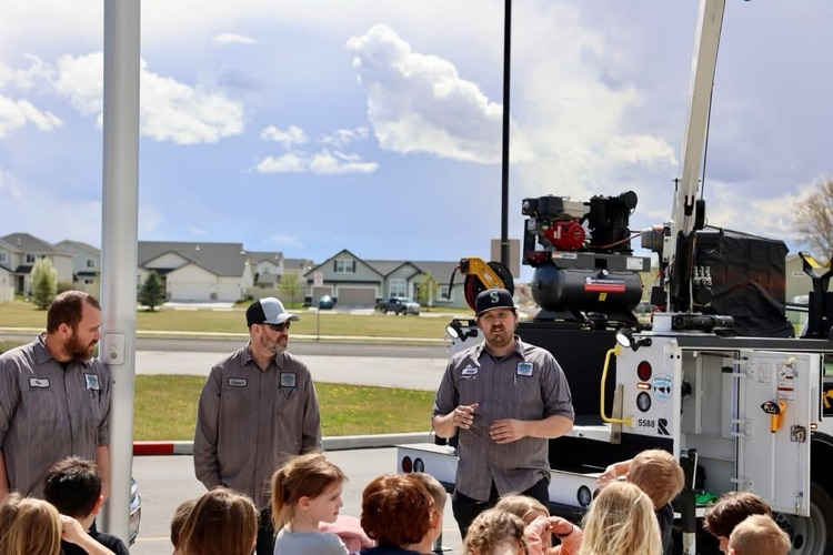 students listening to men talk about a crane