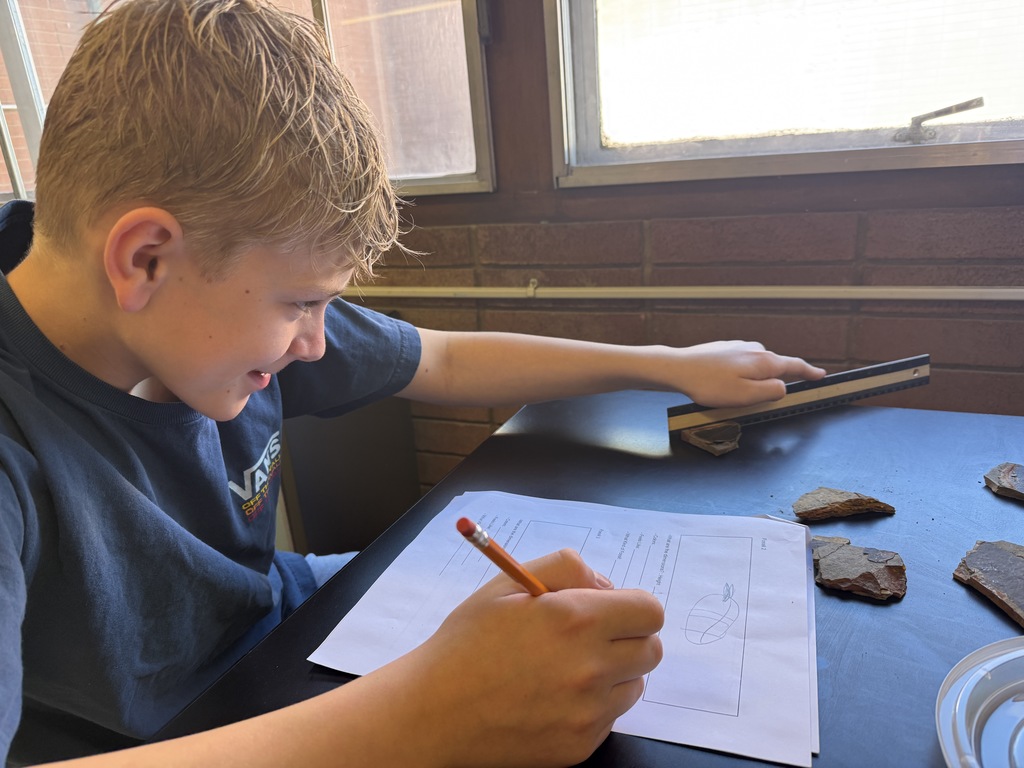 a picture of a male student measuring a rock