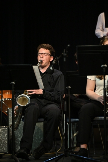 Male student sitting and playing the saxophone