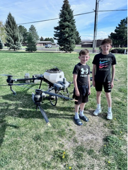 Two students standing next to a drone as big as they are
