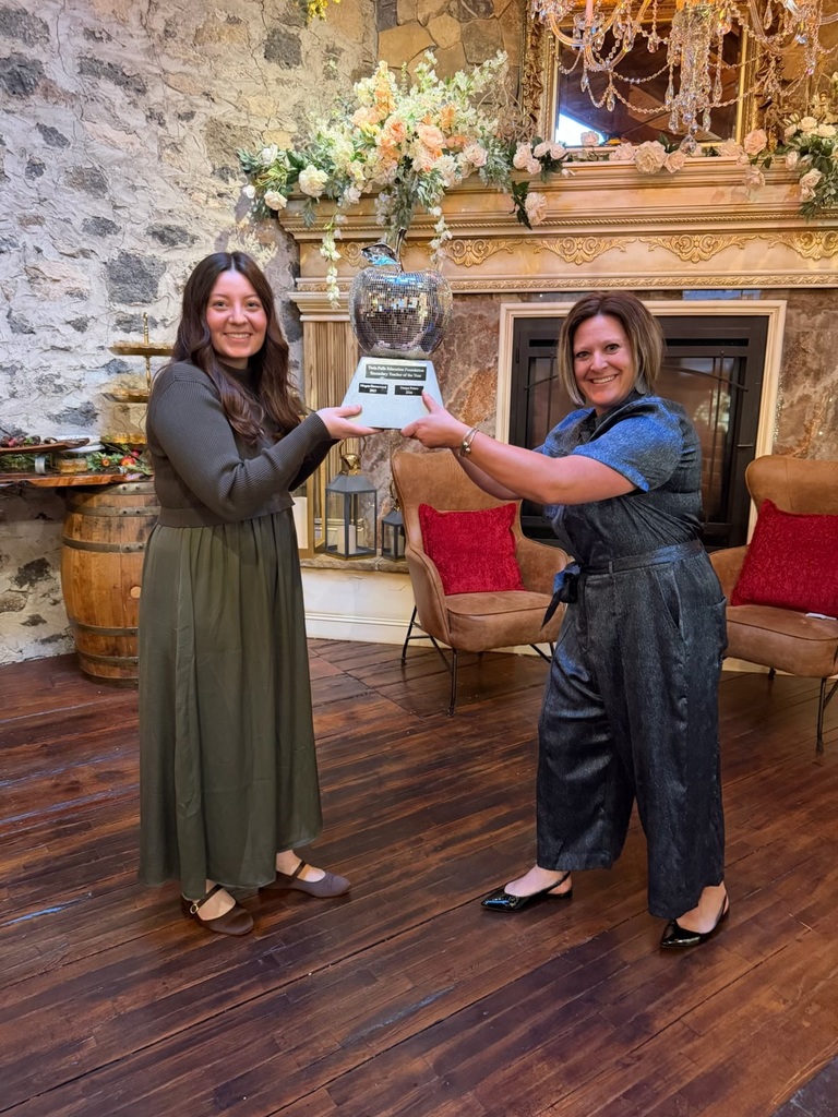 Two snazzy women hold a glittering mirror ball apple in the air