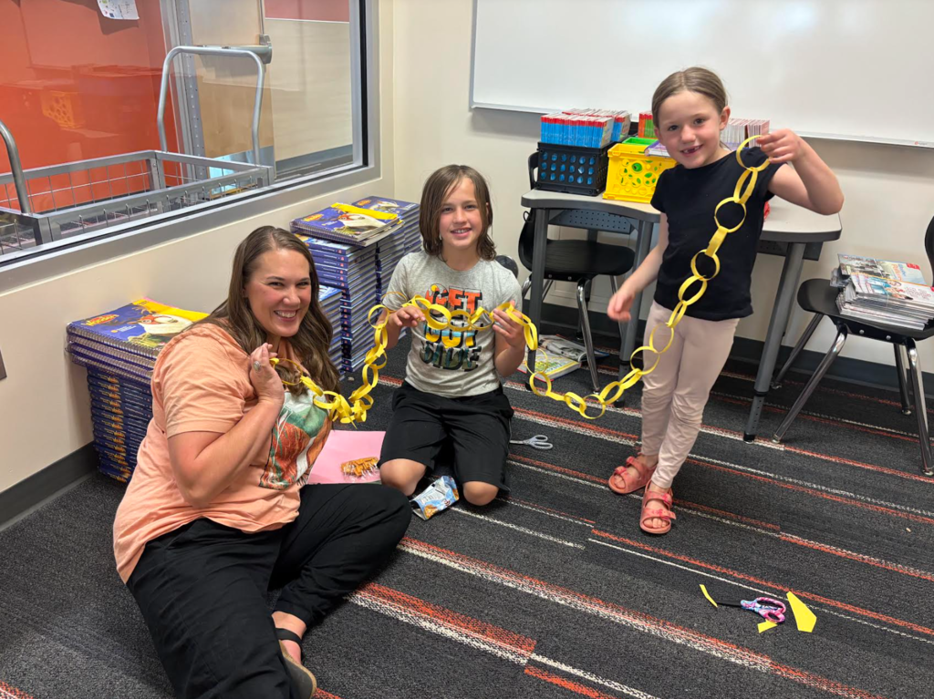 A parent and two students showing us the paper chain they made together