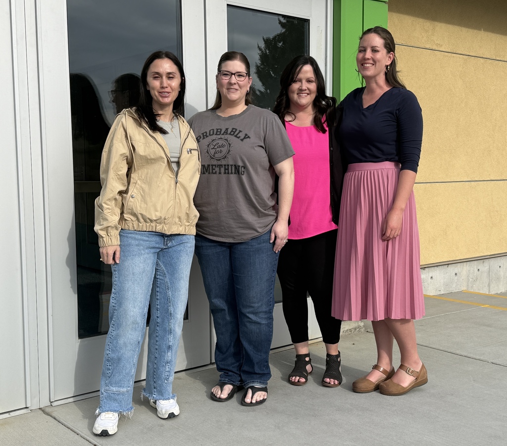A picture of three women standing in front of a school door.