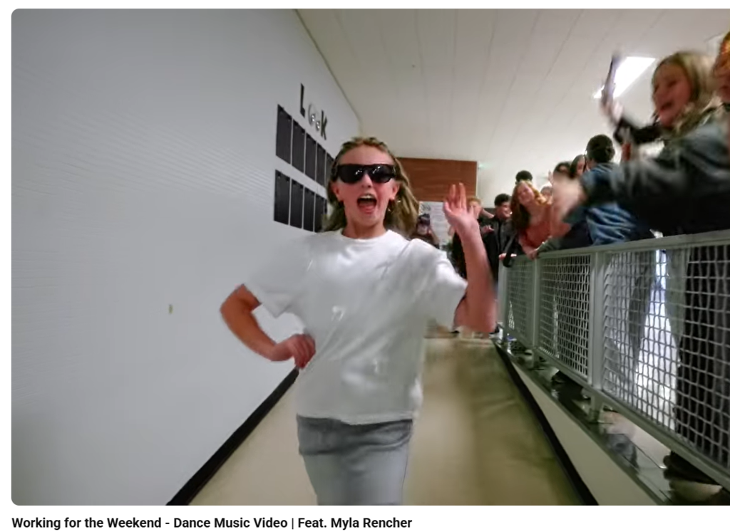 a picture of a female student in a white tshirt and sunglasses walking down the hall