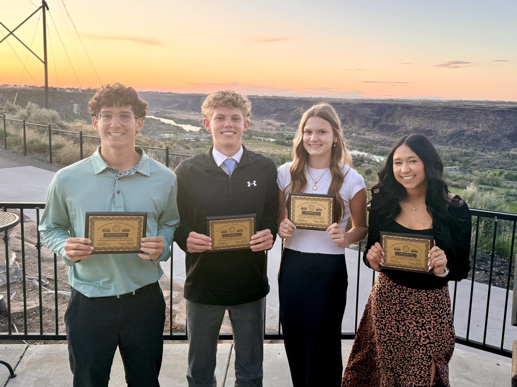 2 boys and 2 girls stand in front of a canyon dressed nicely holding plaques