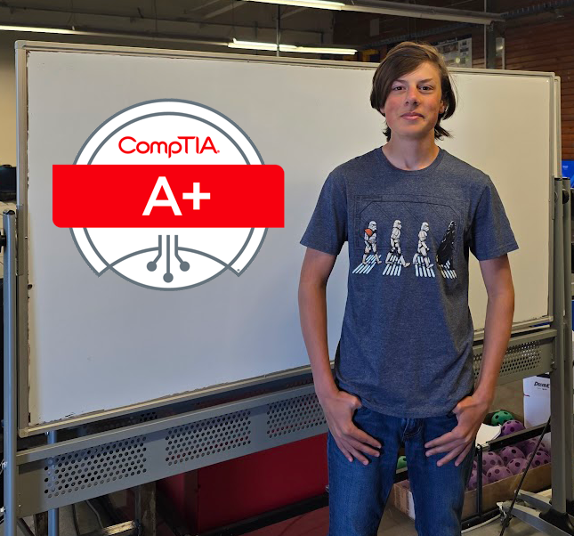 Student stands next to a sign that reads CompTIA A+
