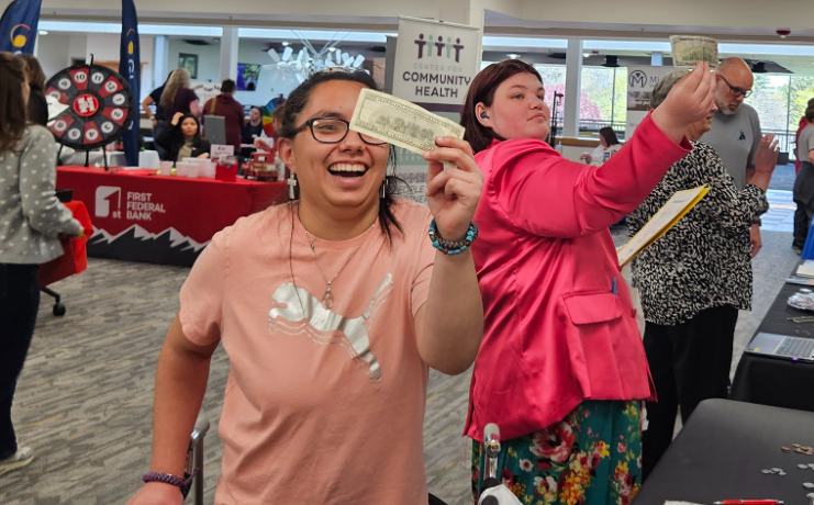 Two students  holding up cash to the light to inspect it.