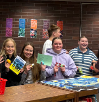 Four students showing their books and prizes to the camera