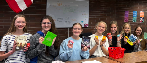 Five students showing their books and prizes to the camera