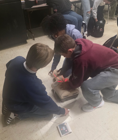 Three students practicing CPR on a dummy