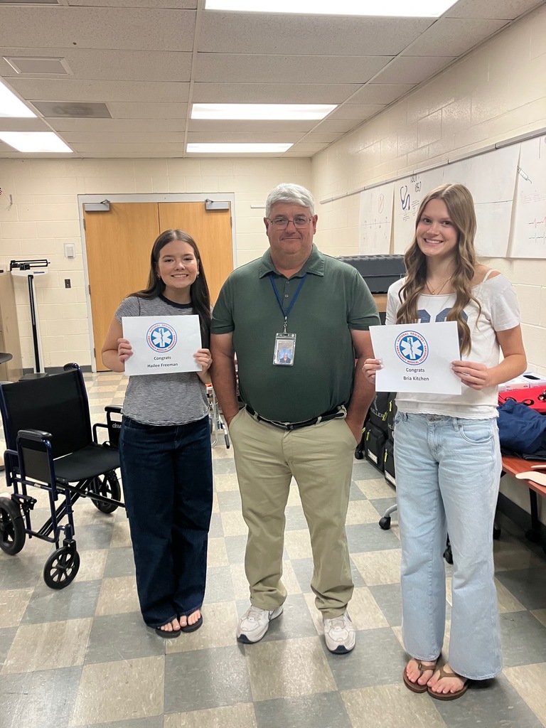 Bria Kitchen and Hailee Freeman standing with Mr. Showers holding their EMT Certification Certificates