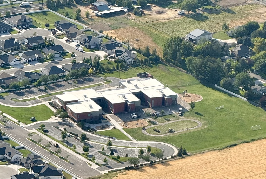 Aerial view of a neighborhood with homes and a large building with a white roof and red accents.
